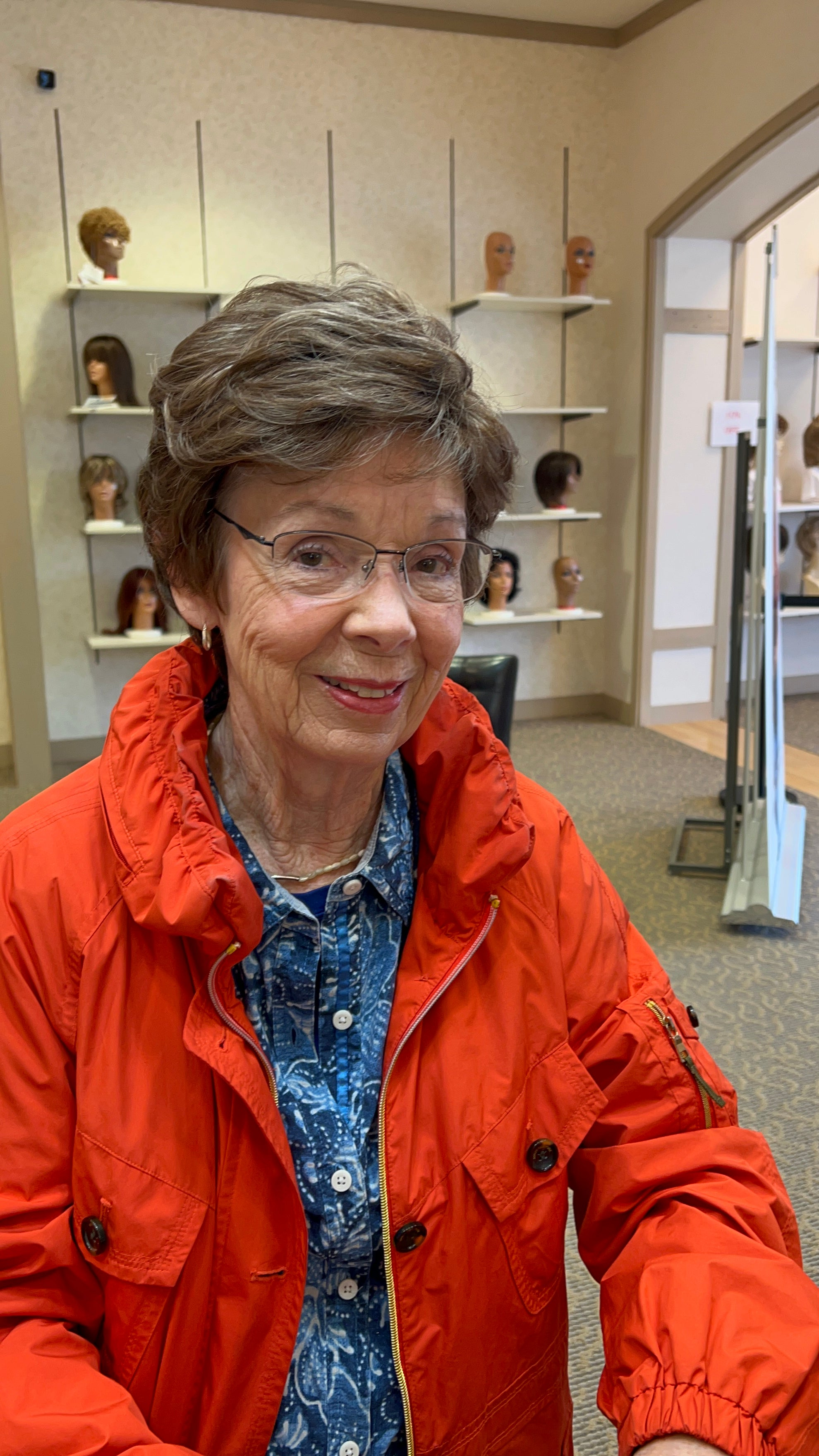 A smiling Caucasian woman with long, silky straight hair styled in a synthetic lace front wig. The hairline appears natural, and the style looks realistic and smooth.